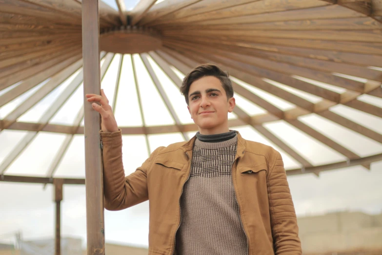 a man standing in front of a wooden structure, by Alexander Fedosav, pexels contest winner, 14 yo berber boy, handsome girl, santiago calatrava, avatar image