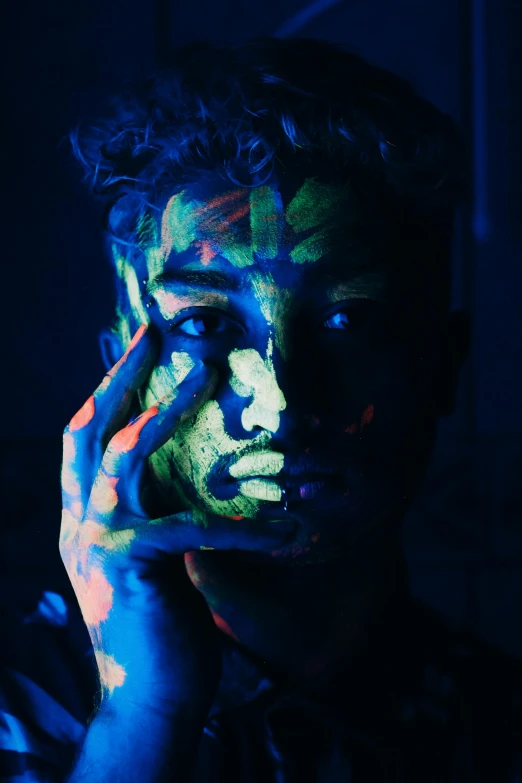 a close up of a person holding a cell phone to their face, an airbrush painting, by Adam Marczyński, trending on pexels, fluorescent spots, portrait of a patchwork boy, blue body paint, made of glowing oil