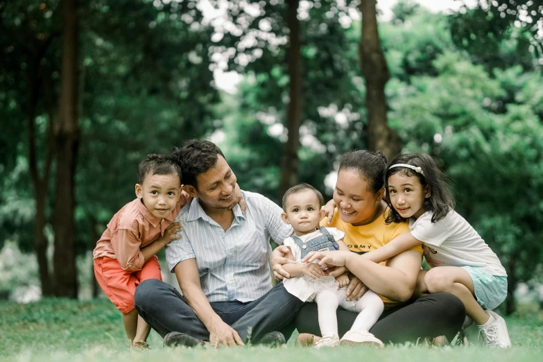 a group of people sitting on top of a lush green field, by Basuki Abdullah, pexels contest winner, hurufiyya, caring fatherly wide forehead, at a park, avatar image, brown