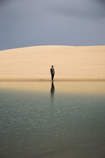 a person standing in the middle of a body of water, inspired by Scarlett Hooft Graafland, australian desert, an arab standing watching over, reflections. shady, in dune