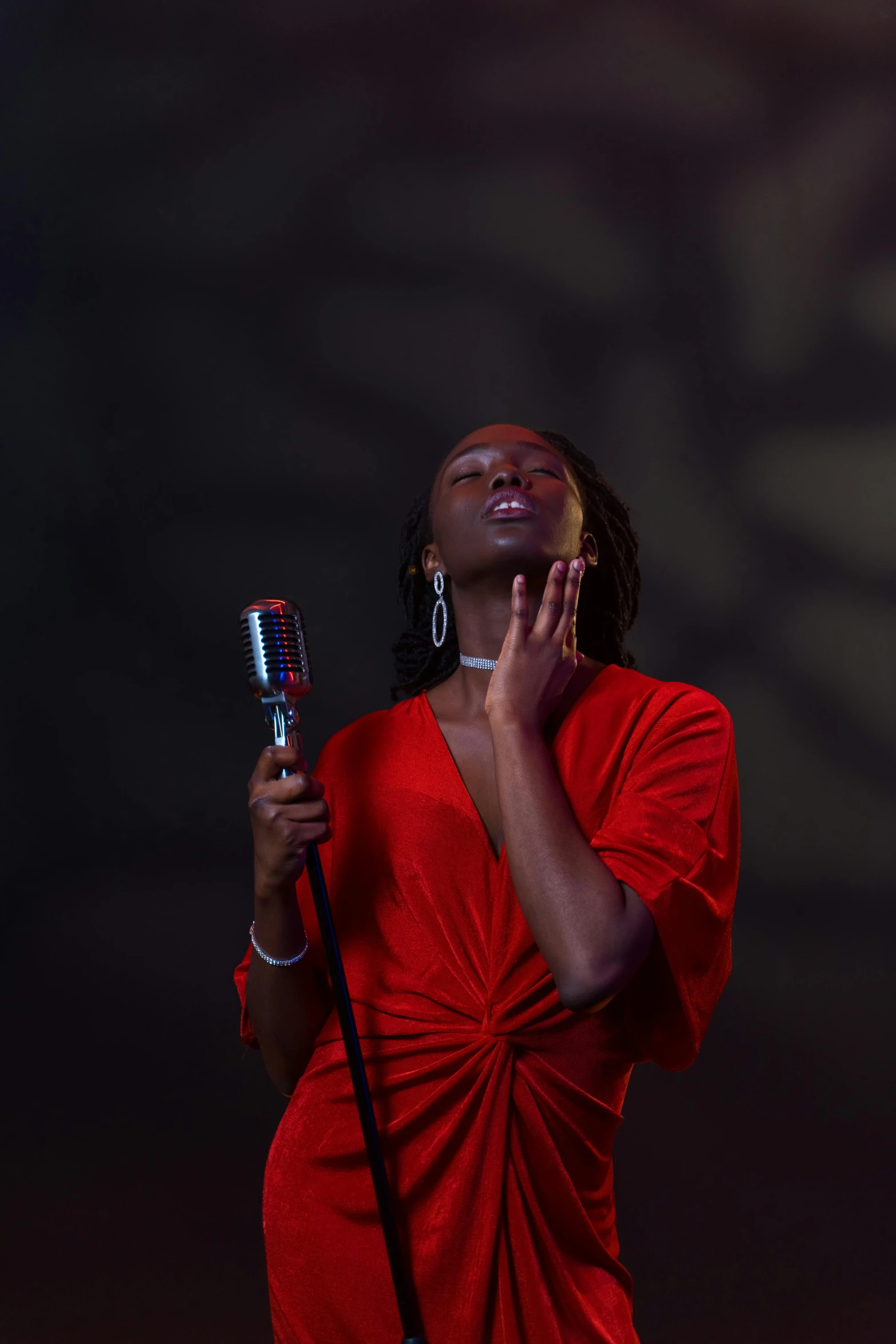 a woman in a red dress holding a microphone, an album cover, pexels, happening, ( ( dark skin ) ), shot with sony alpha 1 camera, square, embracing