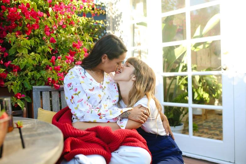 a woman sitting next to a little girl on a bench, kissing each other, manuka, multicoloured, with ivy