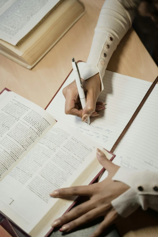 a person sitting at a table with a book and a pen