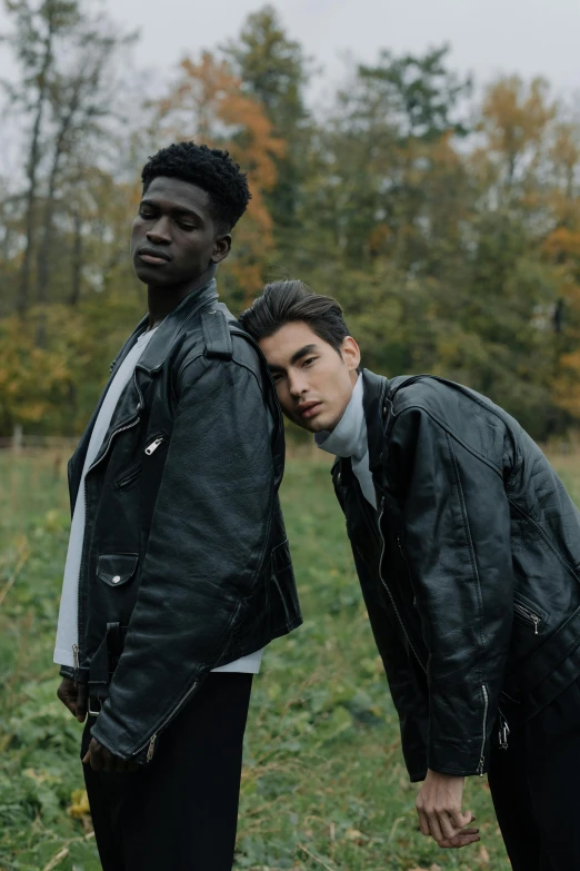 two men standing next to each other in a field, an album cover, by Cosmo Alexander, trending on pexels, renaissance, black leather jacket, high fashion modeling, adut akech, cute boys