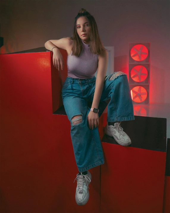 a woman sitting on top of a red wall, an album cover, inspired by Elsa Bleda, trending on pexels, ( ( ( wearing jeans ) ) ), purple volumetric lighting, 🤤 girl portrait, standing in corner of room