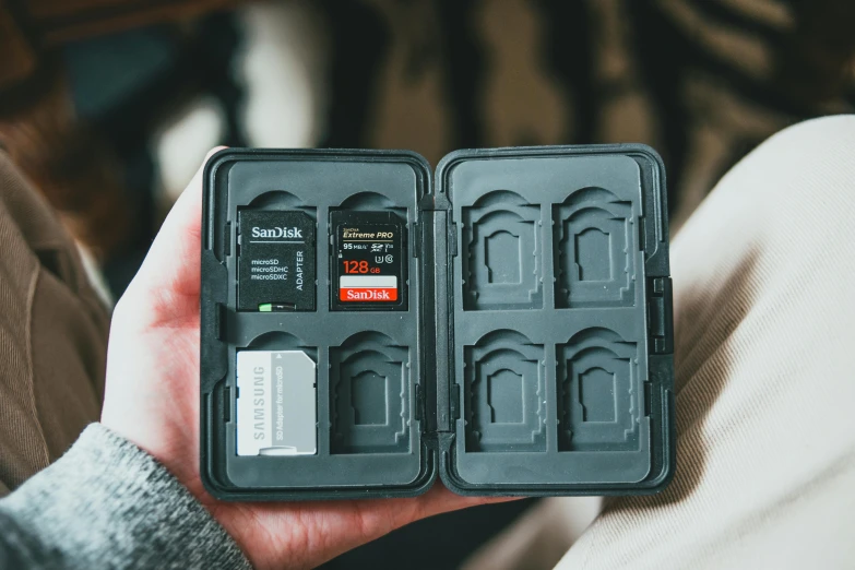 a close up of a person holding a memory card, by Julia Pishtar, unsplash, game case, interior of a small, open vault, on a canva