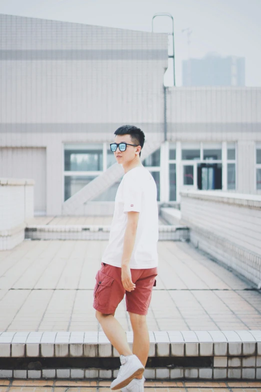 a man in white shirt and red shorts riding a skateboard, inspired by Ding Yunpeng, unsplash, aestheticism, standing on a rooftop, avatar image, wearing square glasses, he is about 20 years old | short