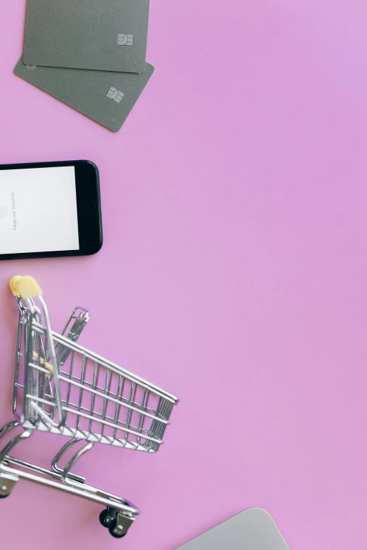 a laptop computer sitting on top of a desk next to a shopping cart, pexels, pink and purple, smartphone, plain background, 1 5 6 6