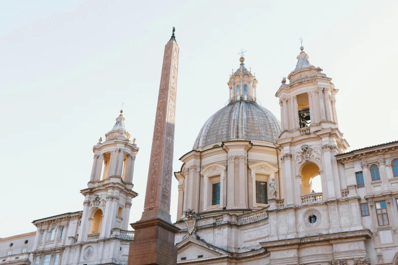 a large building with a tall obelisk in front of it, inspired by Gian Lorenzo Bernini, unsplash contest winner, domes, roman nose, warmly lit, buildings carved out of stone