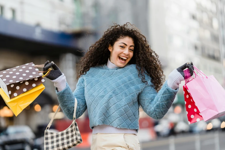 a woman walking down a street holding shopping bags, pexels contest winner, happening, curly haired, overjoyed, square, wearing a sweater