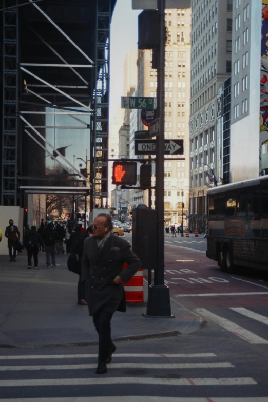 a man walking across a street next to tall buildings, street signs, peter eisenman, bus stop, ignant