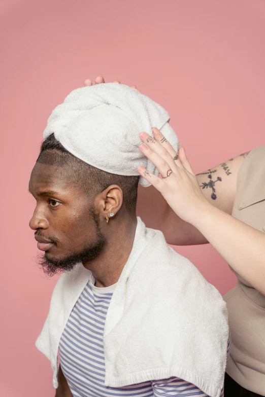 a woman combing a man's hair with a towel, an album cover, by Jessie Alexandra Dick, trending on pexels, diverse, non-binary, hand holding cap brim, headshot profile picture