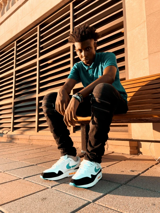a man sitting on a bench in front of a building, an album cover, inspired by Jordan Grimmer, trending on unsplash, white and teal metallic accents, nike air max, 2 1 savage, headshot profile picture