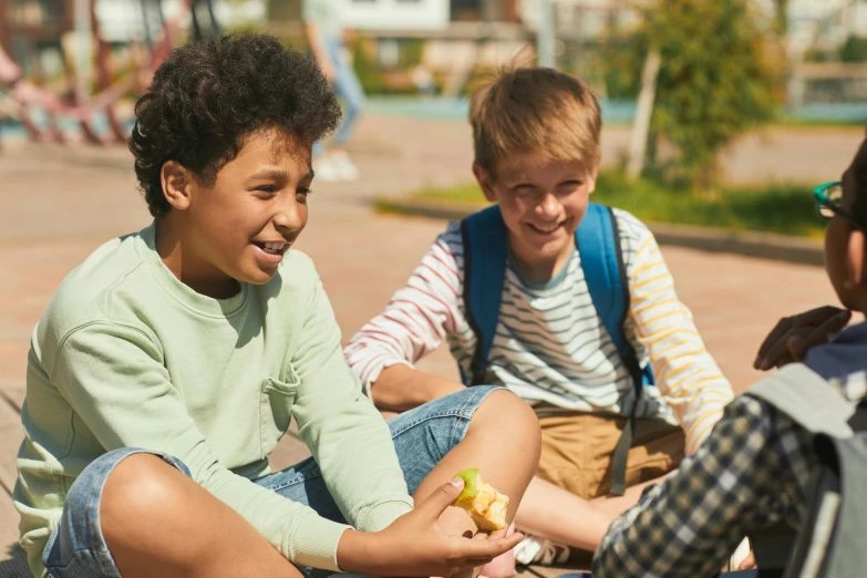 a group of young children sitting next to each other, pexels, happening, school courtyard, snacks, teen boy, a still of a happy