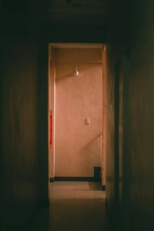 a dark hallway with a light hanging from the ceiling, a picture, inspired by Elsa Bleda, conceptual art, rinko kawauchi, light - brown wall, tall door, 2019 trending photo