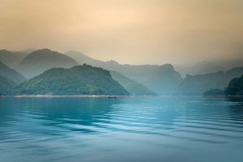 a large body of water with mountains in the background, inspired by Pierre Pellegrini, pexels contest winner, sumatraism, muted colours 8 k, vietnam, early morning light, turquoise horizon