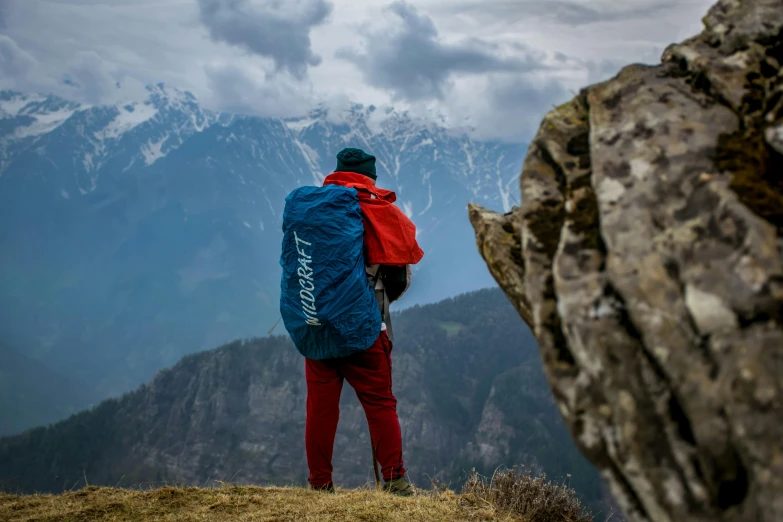 a man with a backpack standing on top of a mountain, by Alexander Runciman, pexels contest winner, indiecraft aesthetic, blue print, a red cape, ready to eat