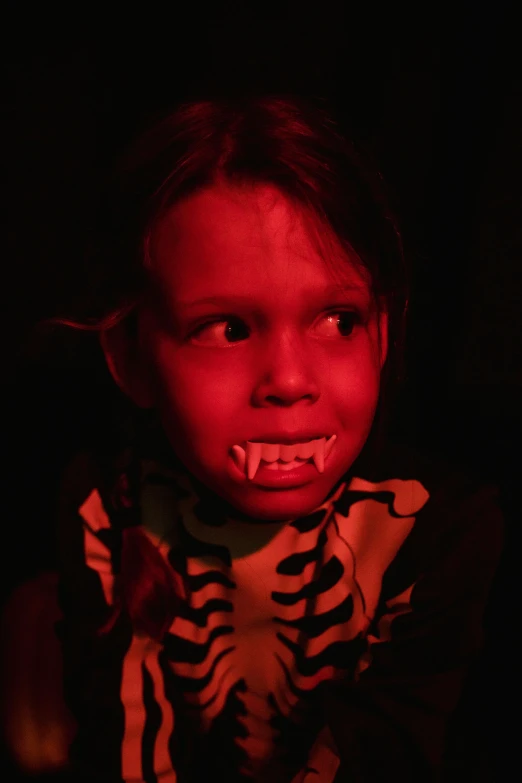 a little girl with a fake skeleton on her face, by Lee Loughridge, symbolism, monster teeth covered in red, aboriginal, glowing in the dark, taken in 2 0 2 0