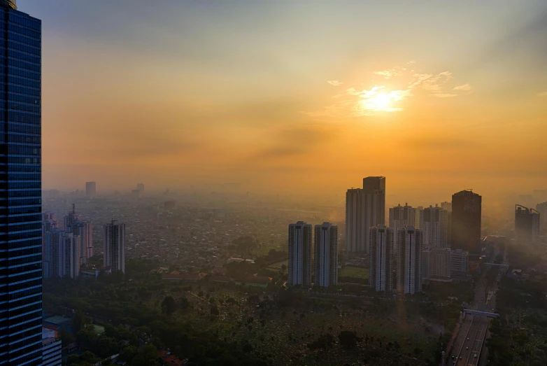 the sun is setting over a city with tall buildings, pexels contest winner, sumatraism, panoramic, very smoky, 2040, drone photograpghy