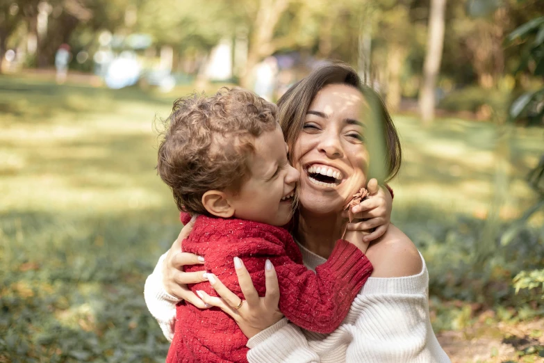 a woman holding a child in front of a mirror, pexels contest winner, having fun in the sun, hugging each other, open happy mouth, in a park