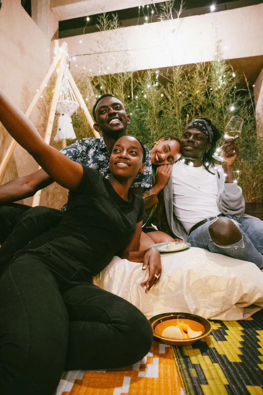 a group of people sitting on top of a bed, by Ingrida Kadaka, trending on unsplash, interior of a tent, with afro, selfie, hollywood promotional image