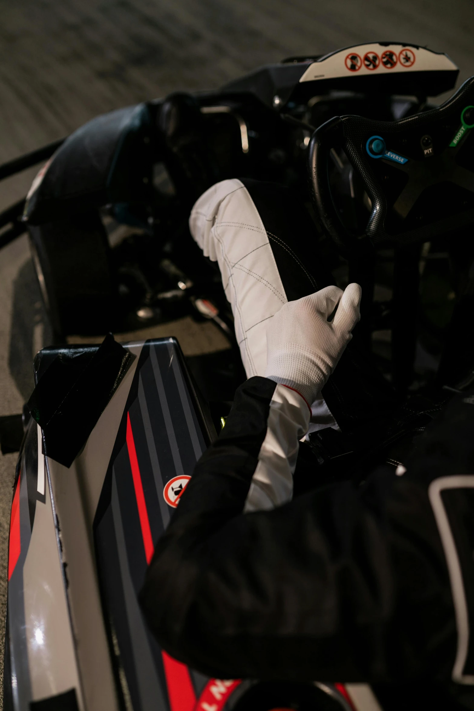 a close up of a person on a motorcycle, wearing gloves, formula 1 garage, hand wraps, (night)