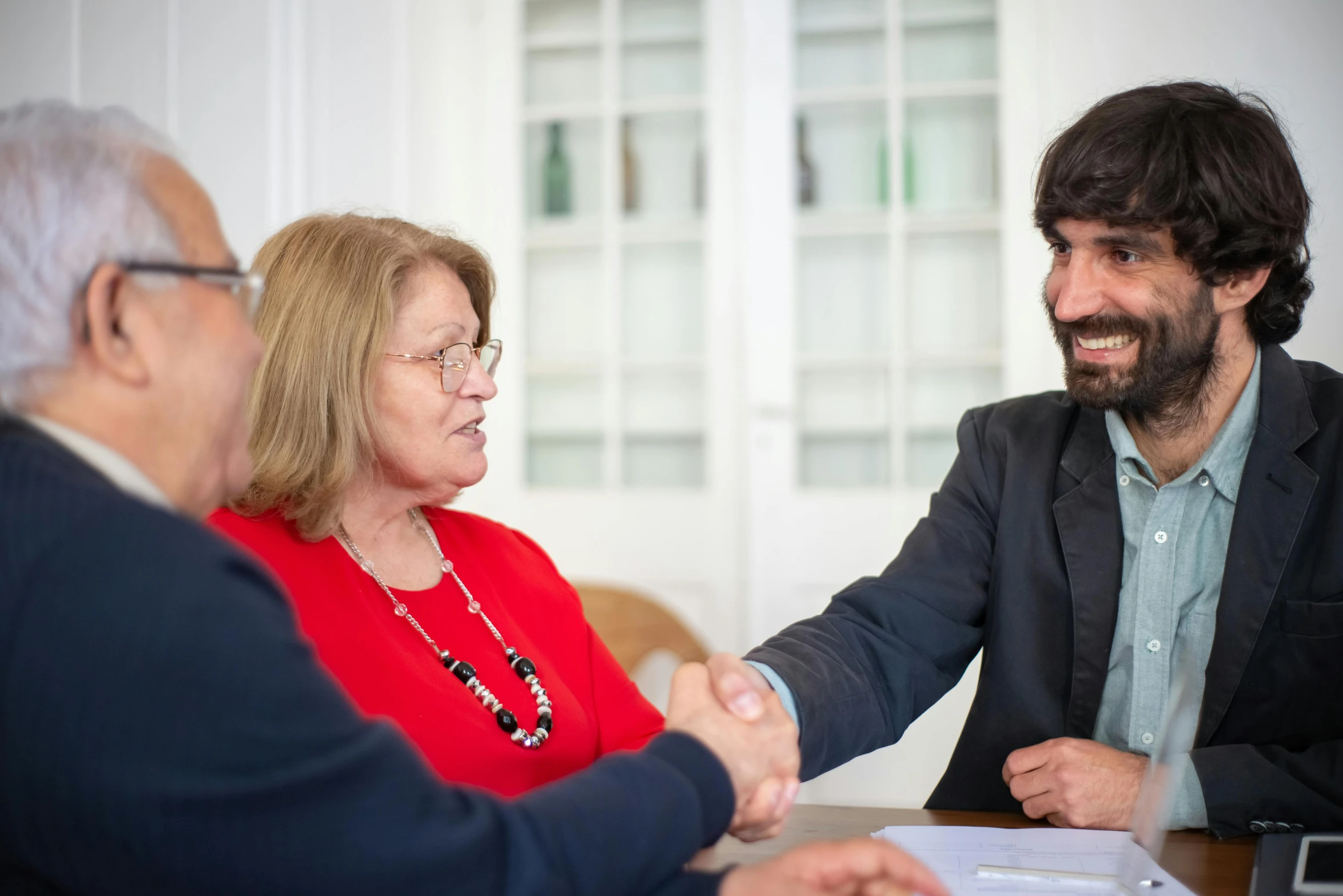 a group of people sitting around a table shaking hands, múseca illil, profile image, thumbnail, portrait image