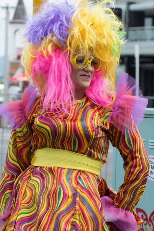 a woman dressed as a clown walking down the street, inspired by Bernd Fasching, pink and yellow, transgender, 'groovy', older woman