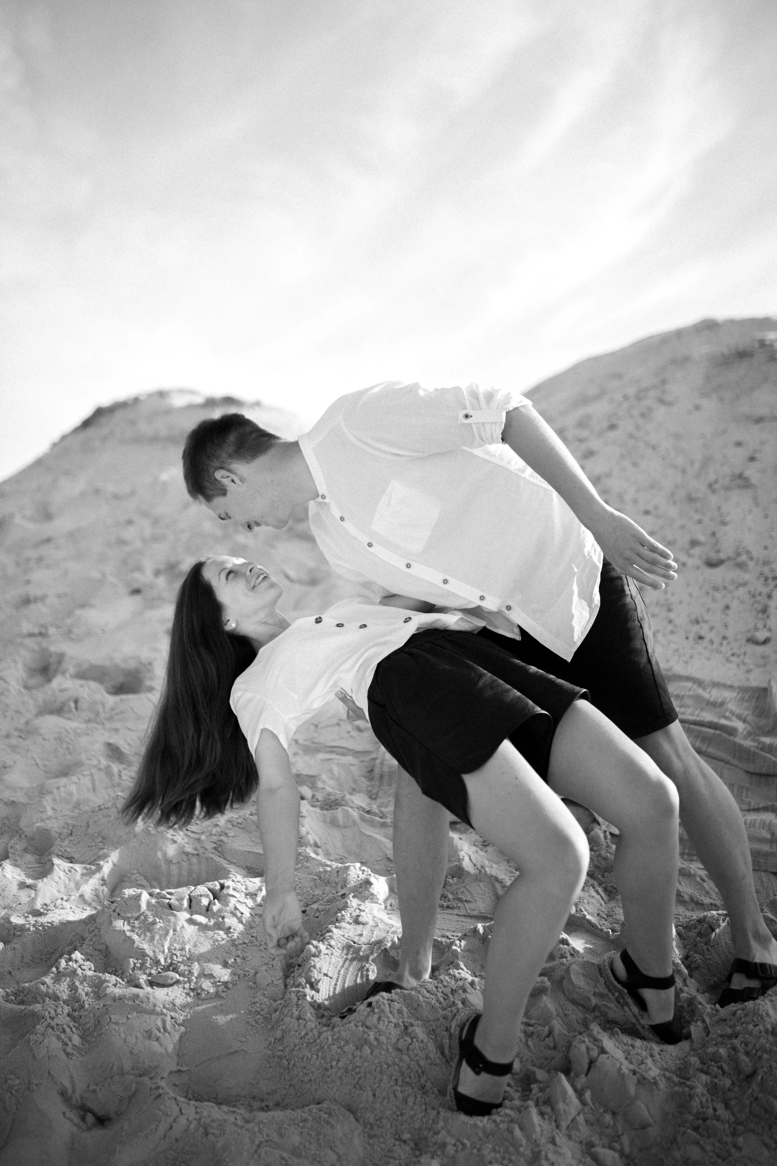 a black and white photo of a couple on the beach, a black and white photo, happening, 👰 🏇 ❌ 🍃, dynamic low angle shot, colored photography, backlight photo sample