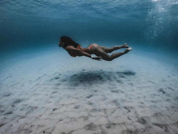 a woman swimming underwater in the ocean, unsplash contest winner, intimidating floating sand, various posed, sydney hanson, slightly tanned