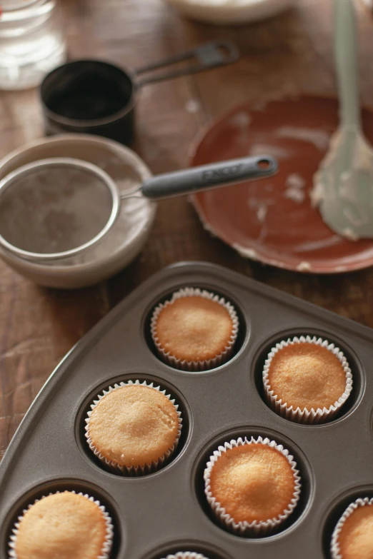 a muffin pan filled with cupcakes sitting on top of a wooden table, inspired by david rubín, dwell, grey, thumbnail, plating