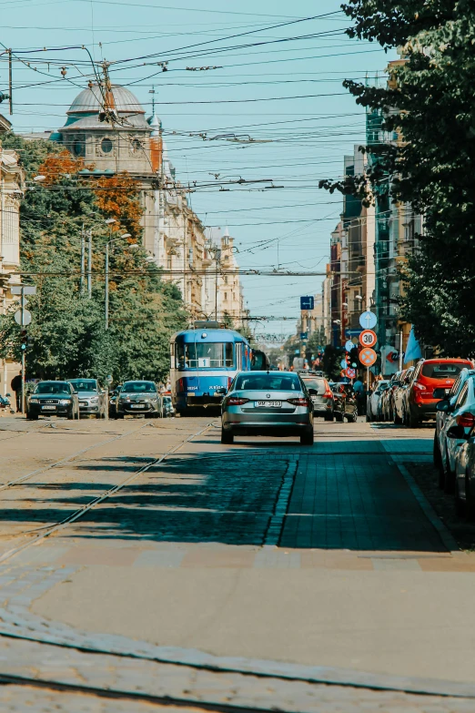a street filled with lots of traffic next to tall buildings, by Adam Marczyński, pexels contest winner, renaissance, lviv, sunny day time, trams, subtitles