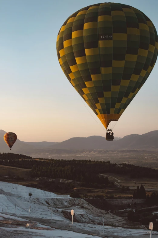 a couple of hot air balloons flying in the sky, a picture, pexels contest winner, happening, overlooking a valley, split near the left, pamukkale, yellow