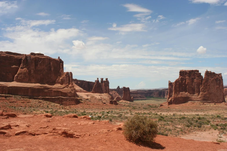 a large rock formation in the middle of a desert, by Linda Sutton, unsplash contest winner, arches adorned pillars, seen from a distance, stephen shore, skyscrapers in the distance