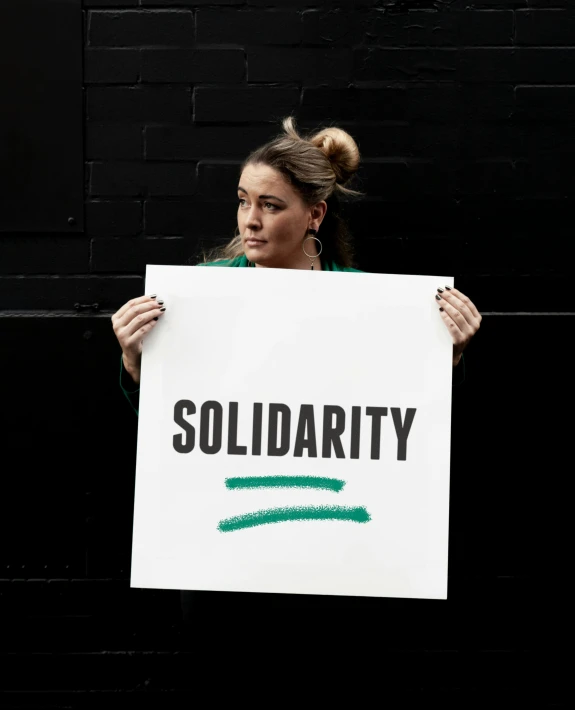 a woman holding a sign that says solidarity, an album cover, unsplash, portrait image, square, florence pugh, white ribbon