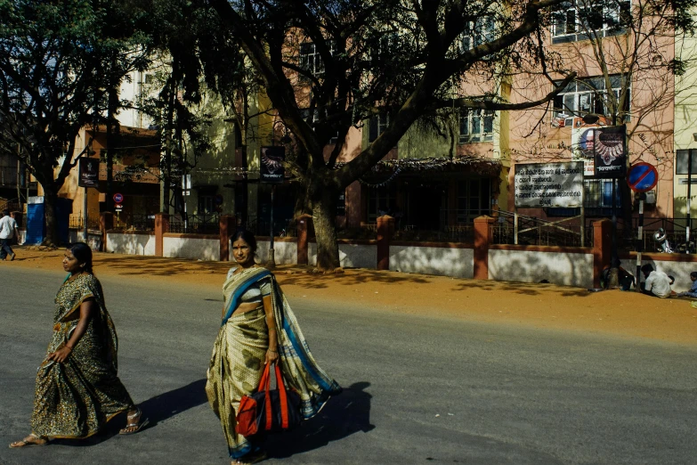 a couple of women walking down a street, pexels contest winner, bengal school of art, in a square, colour photograph, high resolution image, wide film still