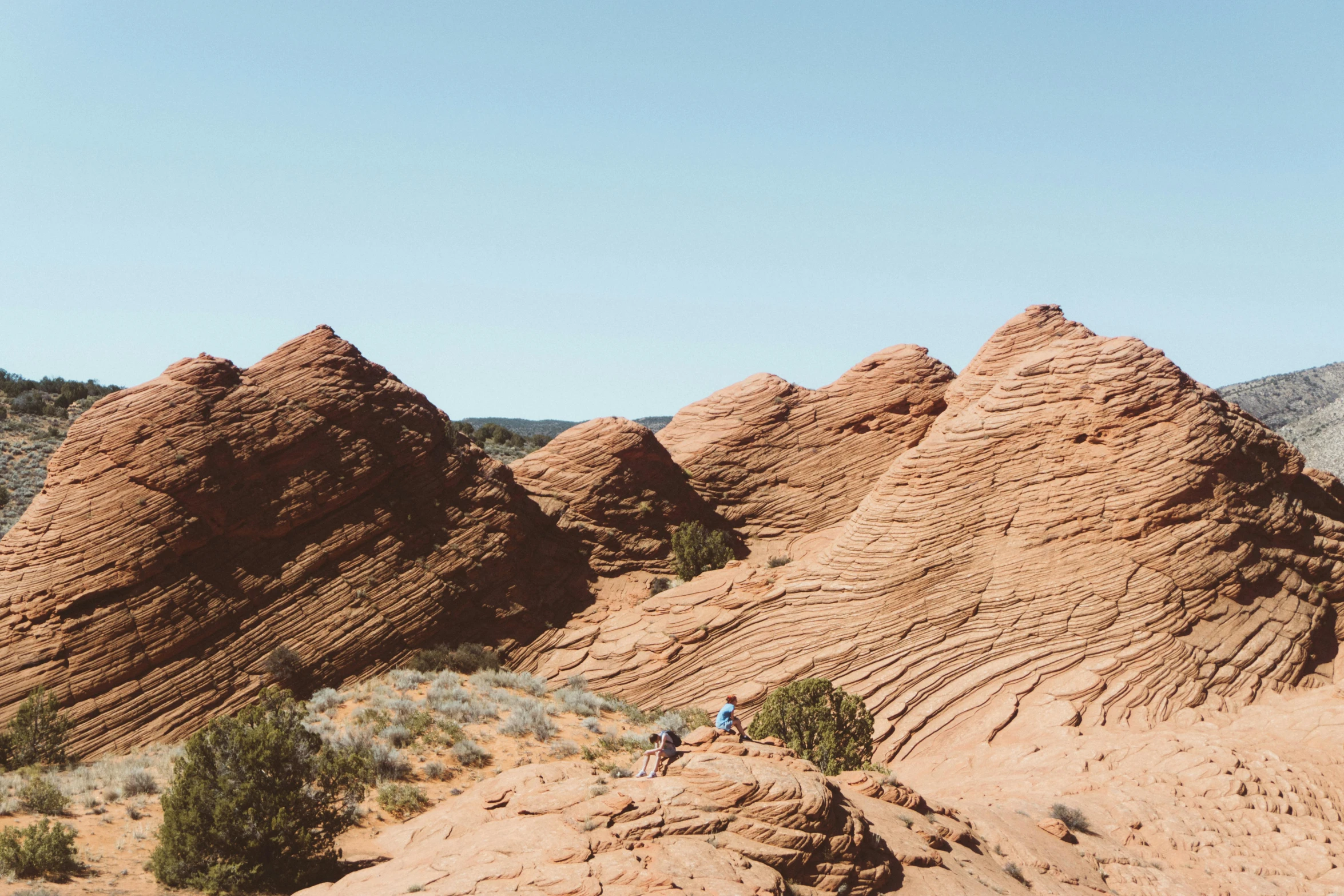 a couple of people that are standing in the dirt, unsplash contest winner, red sandstone natural sculptures, rolling foothills, dwell, afternoon hangout