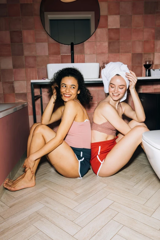 two women sitting on the floor in a bathroom, by Matija Jama, trending on unsplash, renaissance, wearing red shorts, photoshoot for skincare brand, happy friend, posing together in bra