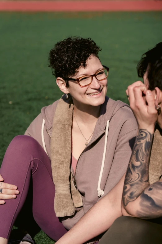 a man and a woman sitting on the grass, a portrait, trending on pexels, non binary model, wears glasses, lesbian, happy cozy feelings