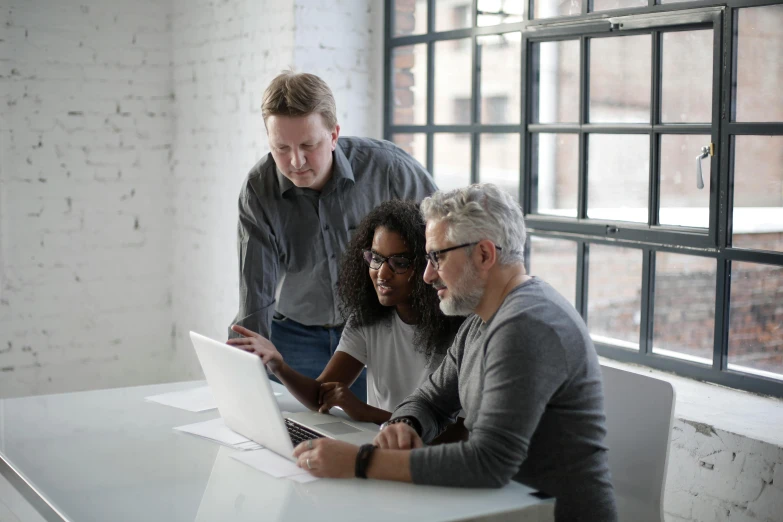 a group of people sitting around a table looking at a laptop, profile image, grey, engineering, rule of three