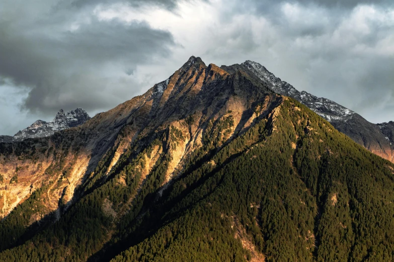 a plane flying over a mountain range under a cloudy sky, an album cover, by Peter Churcher, pexels contest winner, baroque, ominous! landscape of north bend, late afternoon light, brown, the mountain is steep