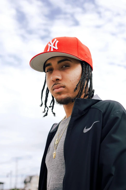 a man with dreadlocks wearing a baseball cap, an album cover, trending on pexels, jayson tatum, looking to camera, skyline, wearing a red backwards cap