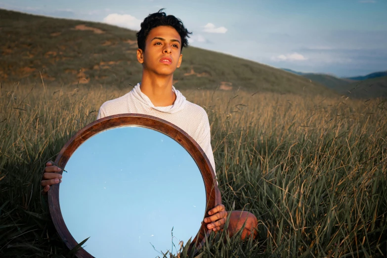 a man holding a mirror in a field, an album cover, inspired by Scarlett Hooft Graafland, pexels contest winner, 14 yo berber boy, light skin, portrait androgynous girl, actor