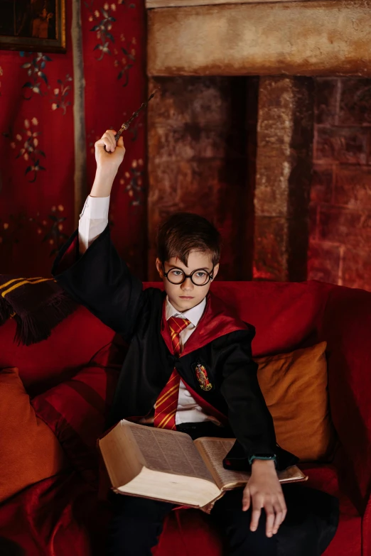 a person sitting on a couch with a book, wizard robes, magical school student uniform, striking a pose, promo image