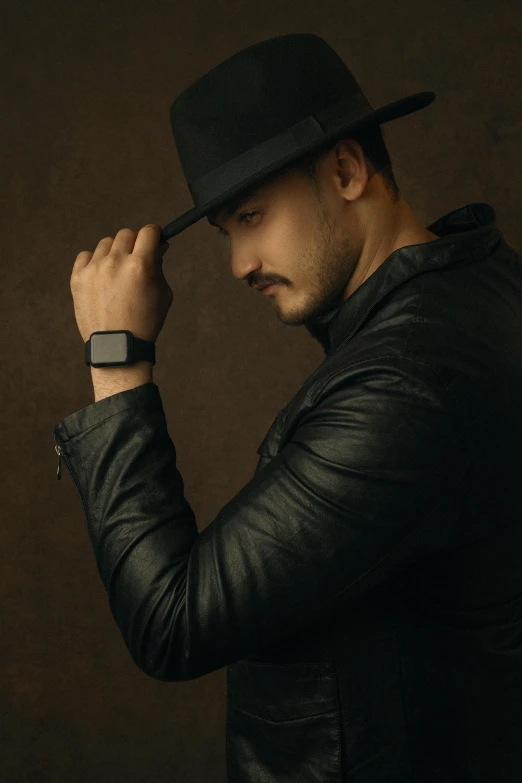 a man wearing a hat and a leather jacket, an album cover, inspired by Carlo Mense, trending on pexels, wears a watch, elegant profile posing, square, raden saleh