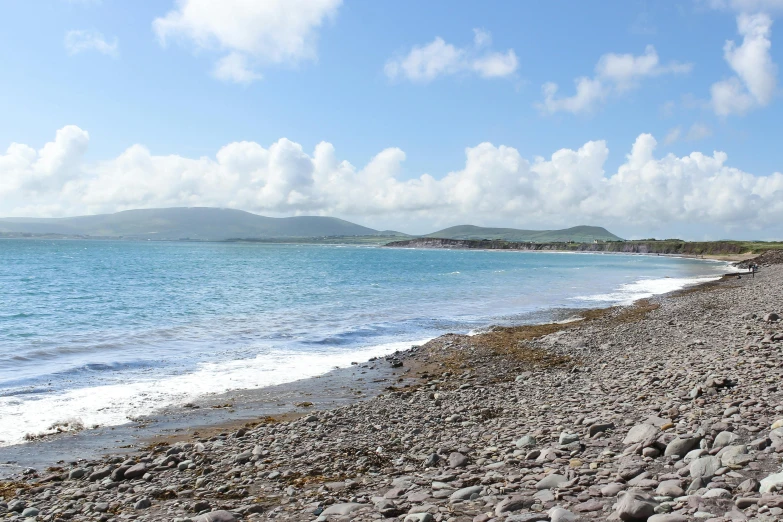 a large body of water sitting on top of a rocky beach, happening, pembrokeshire, ocean in distance, turquoise ocean, mountains and ocean