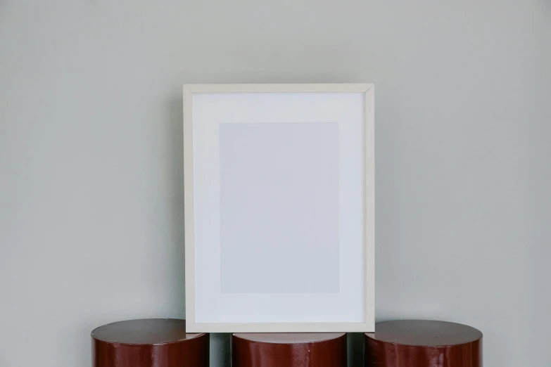 a picture frame sitting on top of three red stools, a minimalist painting, pexels contest winner, light grey backdrop, middle of the page, white wood, graham ingels