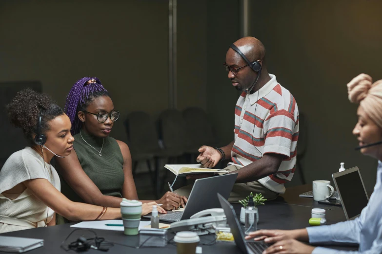 a group of people sitting around a table with laptops, by Everett Warner, pexels contest winner, afrofuturism, teaching, in an office, production photo, avatar image