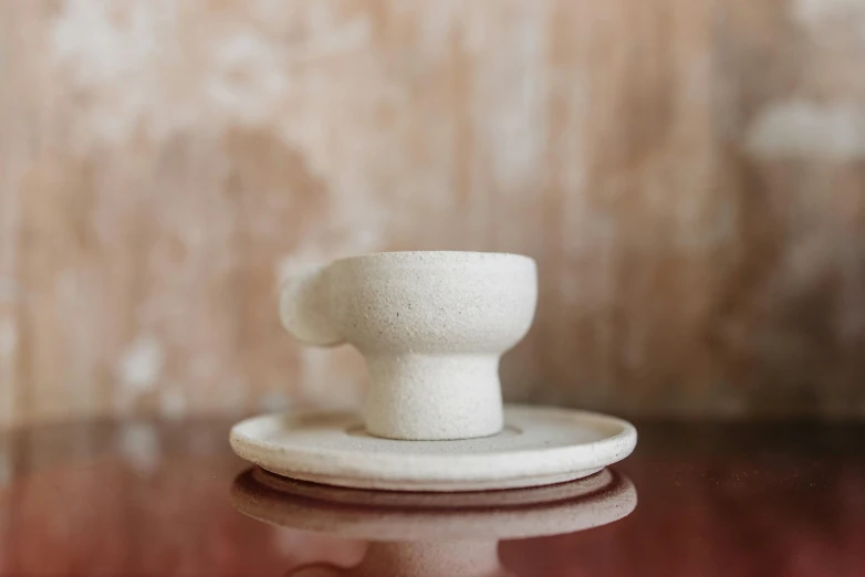 a close up of a cup and saucer on a table, a marble sculpture, inspired by Isamu Noguchi, unsplash, strong eggshell texture, full front view, cast, moroccan