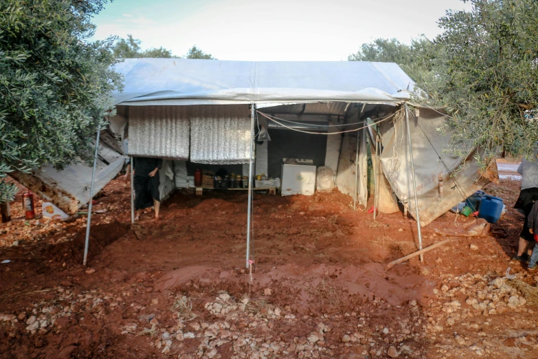 a group of people standing in front of a tent, dau-al-set, metal rust and plaster materials, covered with vegetation, real life photo of a syrian man, exterior wide shot